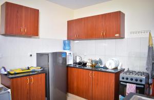 una cucina con armadi in legno e frigorifero in acciaio inossidabile di Cosy House near Airport JKIA Train SGR a Nairobi