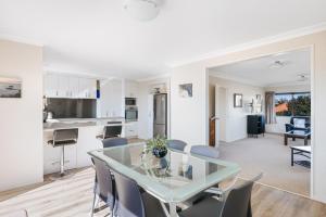 een keuken en een woonkamer met een glazen tafel en stoelen bij Magnificent sunrises, Oceanbeach & Sea Views in Tauranga