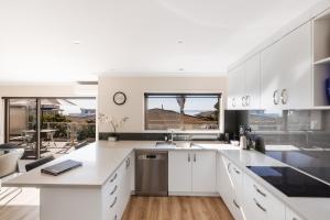 een keuken met witte kasten en uitzicht op een patio bij Magnificent sunrises, Oceanbeach & Sea Views in Tauranga