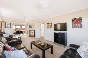 a living room with a couch and a tv at Magnificent sunrises, Oceanbeach & Sea Views in Tauranga