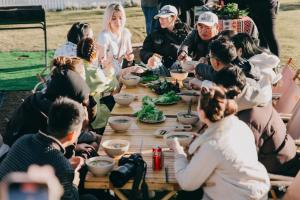 un grupo de personas sentadas alrededor de una mesa comiendo comida en Cloud9 Glamping & Cafe en Xuân Trường