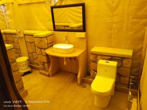 a bathroom with a sink and a toilet and a mirror at Thar Royal Desert Camp in Sām