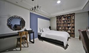 a bedroom with a large white bed and a mirror at Changwon Hotel Baba in Changwon