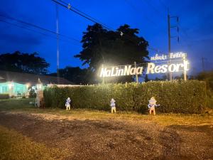 Tre bambini in piedi davanti a una siepe con un cartello di NaLinNaa Resort Buriram ณลิ์ณน่า รีสอร์ท บุรีรัมย์ a Buriram