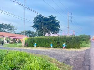 drei Kinder stehen vor einer Hecke in der Unterkunft NaLinNaa Resort Buriram ณลิ์ณน่า รีสอร์ท บุรีรัมย์ in Buriram