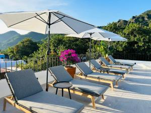 - une rangée de chaises et de parasols sur la terrasse dans l'établissement Tatala Hotel & Garden, à Tepoztlán