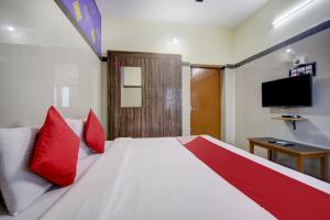 um quarto com uma cama com almofadas vermelhas e uma televisão em Super OYO Green Park em Vellore