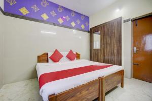 een slaapkamer met een groot bed met rode kussens bij Super OYO Green Park in Vellore