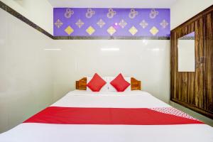 a bedroom with a white bed with red pillows at Super OYO Green Park in Vellore