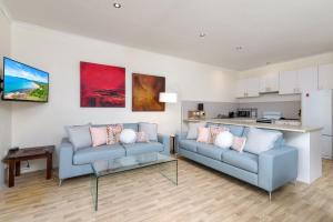 sala de estar con 2 sofás azules y cocina en Villa 5 Marlin Terraces, en Port Douglas