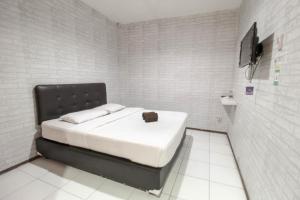 a small bedroom with a bed with a black headboard at Bwalk Hotel Malang in Sengkaling