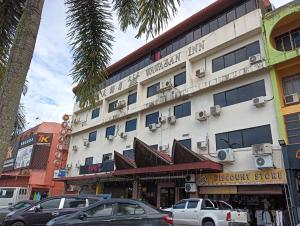 un grande edificio bianco con macchine parcheggiate di fronte di OYO 90860 Wawasan Inn a Sarikei