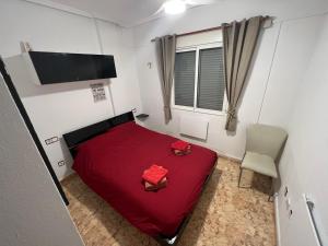 1 dormitorio con 1 cama roja y 1 silla en Saint James Park downstairs, en Orihuela