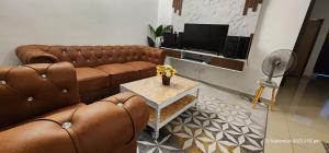 Padang Serai的住宿－D'Haty Homestay，客厅配有2张棕色皮沙发和1张桌子