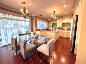 a kitchen and dining room with a glass table and chairs at Vancouver Luxury Homestay in Richmond