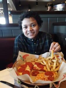 un hombre sentado en una mesa con un plato de pizza y papas fritas en Missouri Holiday Homes LLC, 