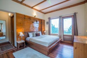 ein Schlafzimmer mit einem großen Bett und einem großen Fenster in der Unterkunft StayVista at Under The Pines in Shimla