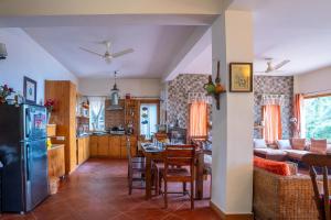 eine Küche und ein Wohnzimmer mit einem Tisch und einem Kühlschrank in der Unterkunft StayVista at Under The Pines in Shimla