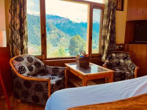 a room with a bed and a table and a window at Shree Ram Cottage, Manali ! 1,2,3 Bedroom Luxury Cottages Available in Manāli