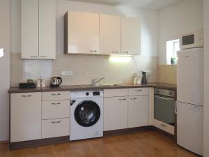 a kitchen with white cabinets and a washing machine at Janka Apartment in Bratislava
