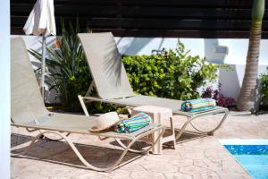 two lounge chairs sitting next to a swimming pool at Narcissos Villa Doria in Protaras