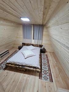 ein Schlafzimmer mit einem Bett in einem Holzzimmer in der Unterkunft Cazare La Nea Marin A Frame in Ciobotani