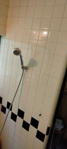 a shower in a bathroom with black and white tiles at きっとあい楽館 in Chichibu