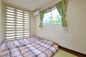 1 dormitorio con cama y ventana en Orchid house, en Nakijin