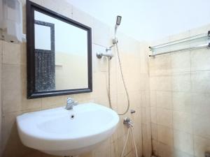 ein Badezimmer mit einem weißen Waschbecken und einem Spiegel in der Unterkunft RedDoorz Syariah near Rumah Sakit Umum Wisata UIT in Balangberu