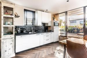 阿斯米尔Beautiful Water Villa, near Schiphol and Amsterdam的厨房配有白色橱柜和黑色台面 更多32张照片
