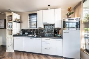 阿斯米尔Beautiful Water Villa, near Schiphol and Amsterdam的带白色橱柜和水槽的厨房