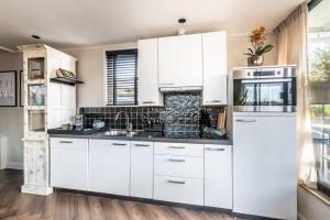 a kitchen with white cabinets and a sink at Beautiful Water Villa, near Schiphol and Amsterdam in Aalsmeer