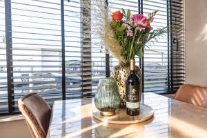 una mesa con una botella de vino y un jarrón con flores en Beautiful Water Villa, near Schiphol and Amsterdam en Aalsmeer