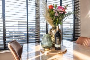 阿斯米尔Beautiful Water Villa, near Schiphol and Amsterdam的一张桌子,上面放着一瓶葡萄酒和花瓶