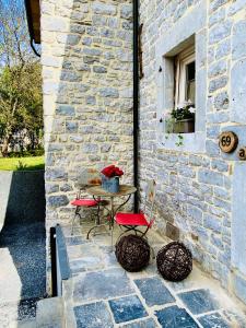 een patio met een tafel en stoelen in een stenen muur bij Thermes du Ninglinspo in Sprimont