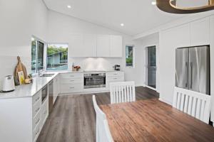 cocina con armarios blancos y suelo de madera en Willy Wagtail @ Cape Villas, en Dunsborough