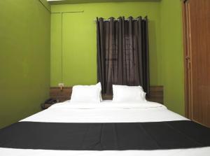 a bedroom with a large bed with green walls and a window at B&B HOMES Guwahati in Guwahati