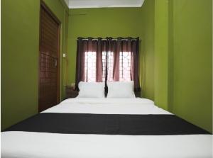 a bed in a green bedroom with a window at B&B HOMES Guwahati in Guwahati