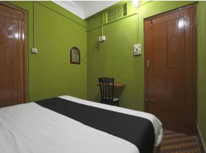 a green bedroom with a bed and a wooden door at B&B HOMES Guwahati in Guwahati
