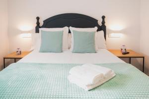 a bed with a green blanket and two pillows on it at Apartamentos Luis in Arzúa