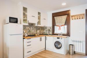 a kitchen with white cabinets and a washer and dryer at Apartamentos Luis in Arzúa