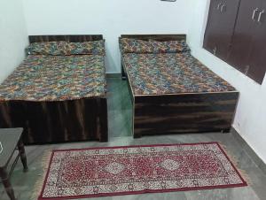 two beds in a room with two rugs at Laxman Guest House in Varanasi