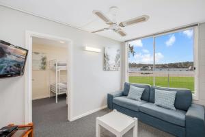 a living room with a blue couch and a window at Fishpen Holiday Apartments in Merimbula