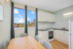 a kitchen with a table and a large window at Fishpen Holiday Apartments in Merimbula