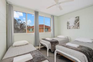 um quarto com três camas e uma janela em Fishpen Holiday Apartments em Merimbula