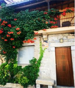 a building with red flowers on the side of it at Casa Rural el Comercio Sierra de Francia in San Miguel de Valero