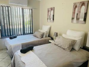 two beds sitting in a room with windows at Beytell's Nest in Richards Bay
