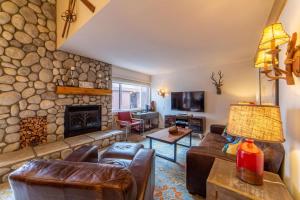 uma sala de estar com lareira de pedra e mobiliário de couro em #381 - Ski-In Ski-Out Condo with Spa, Game Room, & Pool em Mammoth Lakes