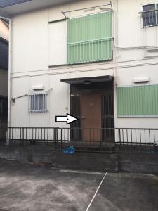 una puerta abierta de un edificio con una flecha apuntando a un estacionamiento en Family Resort Apartment en Funabashi