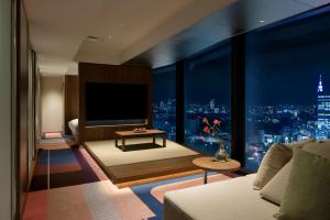 uma sala de estar com vista para a cidade à noite em HOTEL GROOVE SHINJUKU, A PARKROYAL Hotel em Tóquio